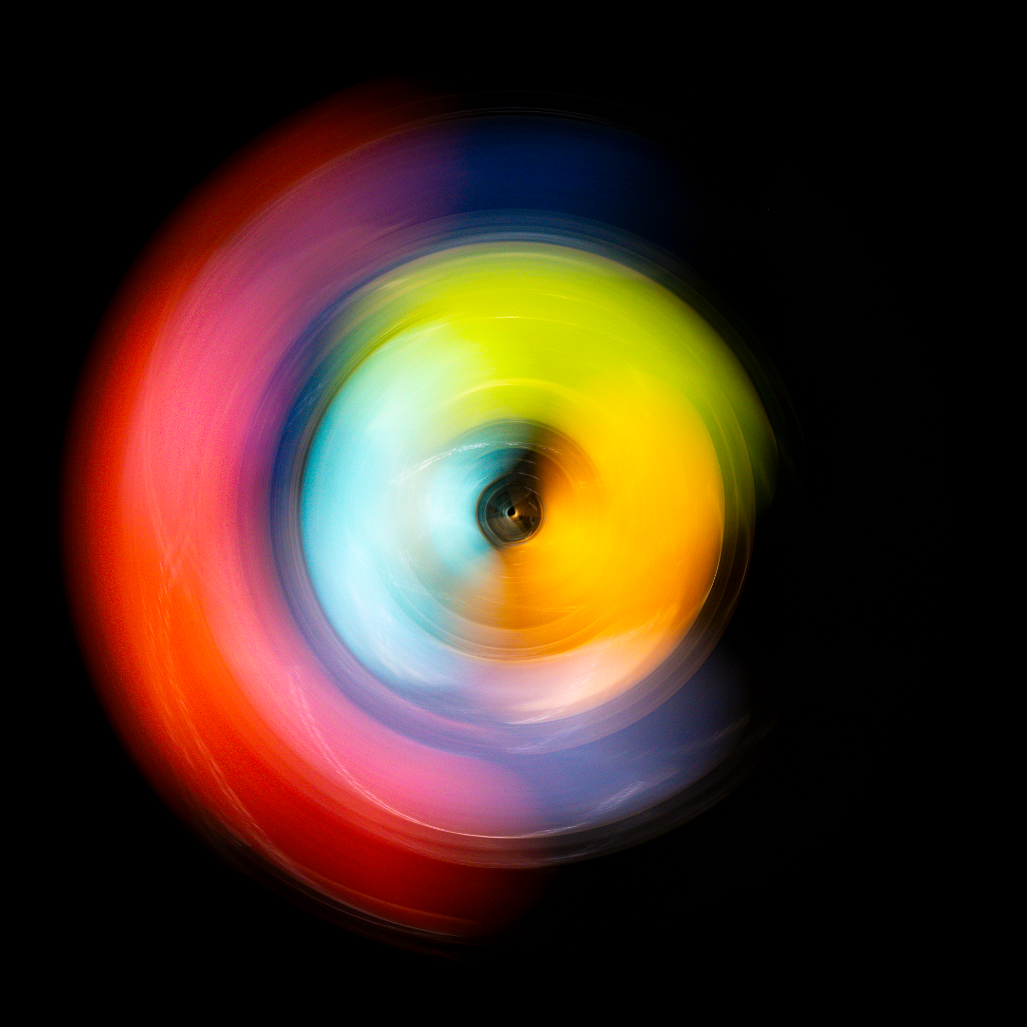 Abstract radial photograph showing a coral colored band at center transitioning outward to cobalt blue edges with dark void at center