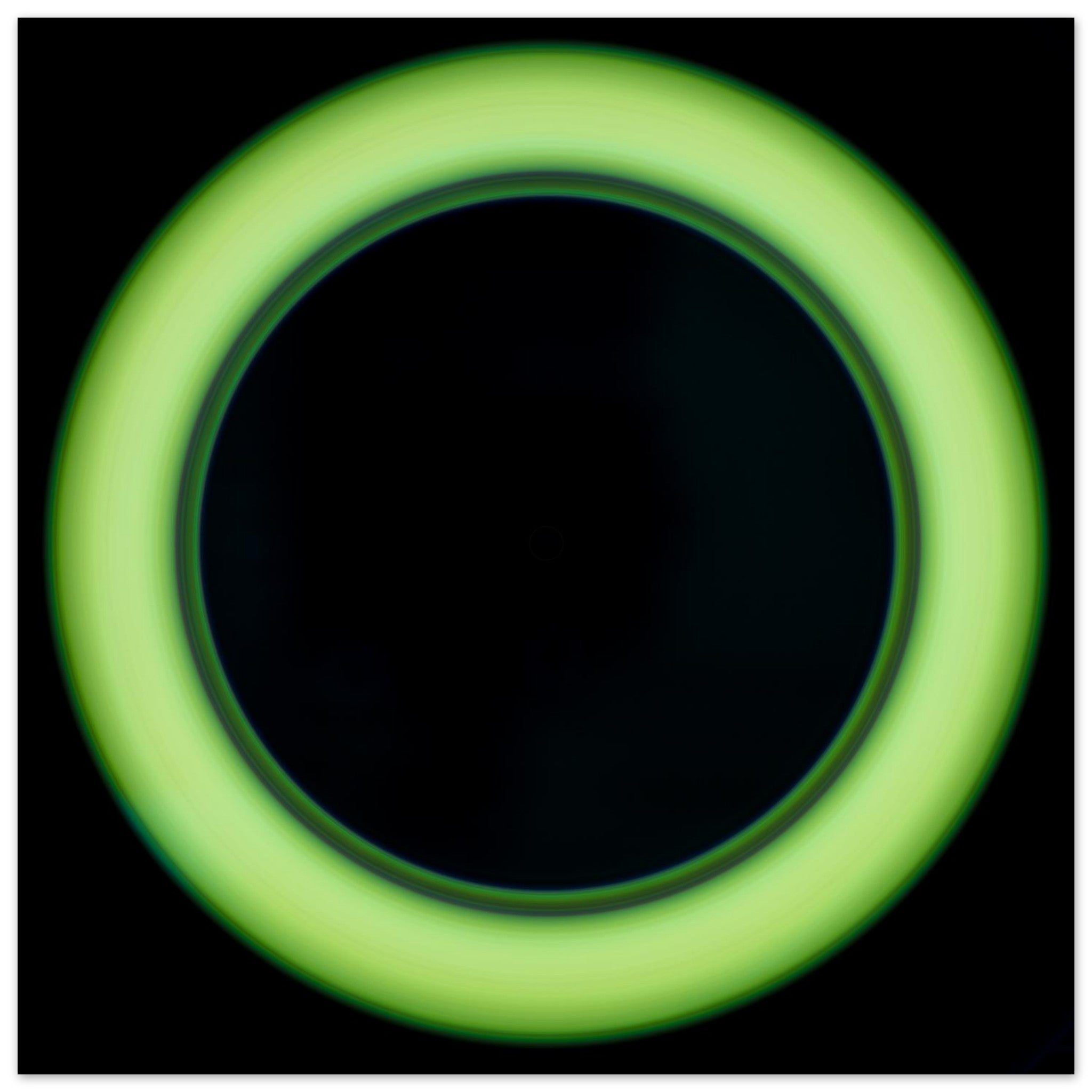A bright lime green circular ring shape with a large black center and soft glowing edges against a black background.